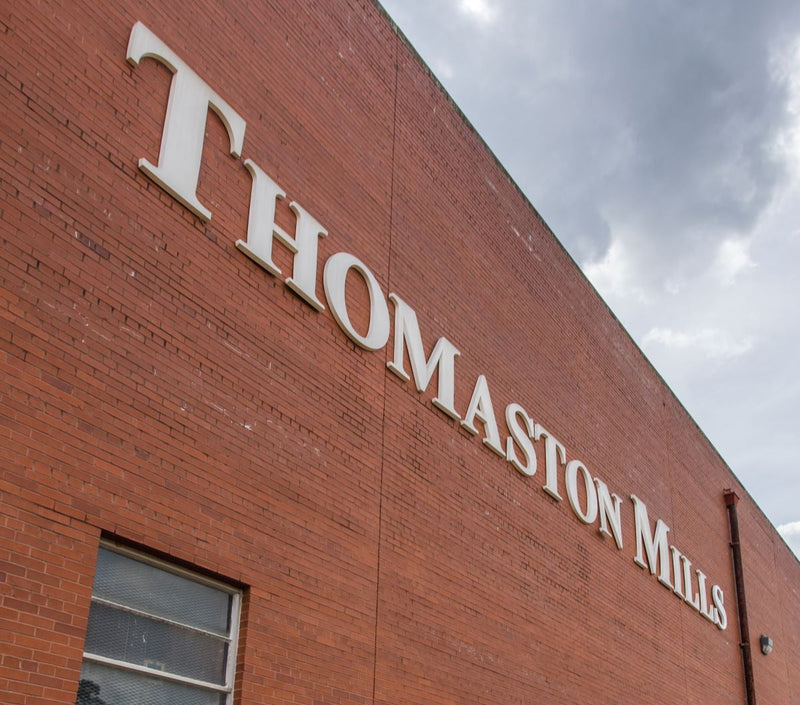 Brick building with 'Thomaston Mills' signage on a cloudy day