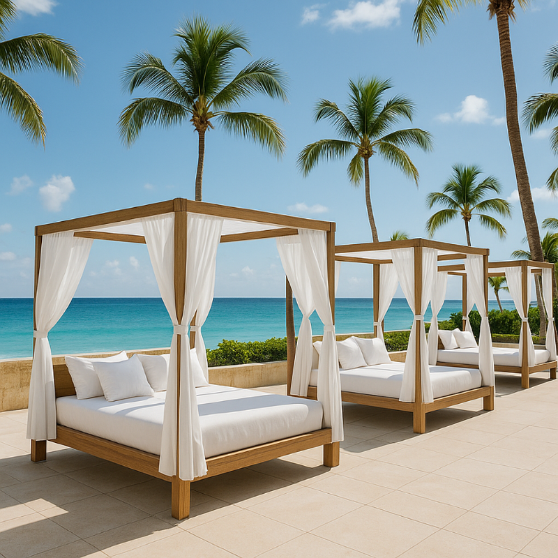 Two wooden canopy beds with white bedding on a patio overlooking the ocean with palm trees in the background.