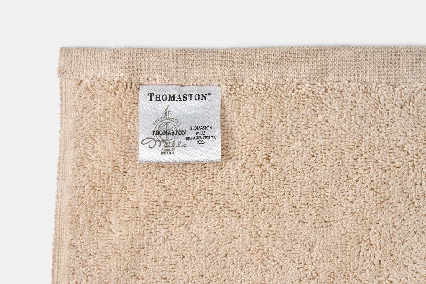 Beige towel with a Thomaston label on a white background