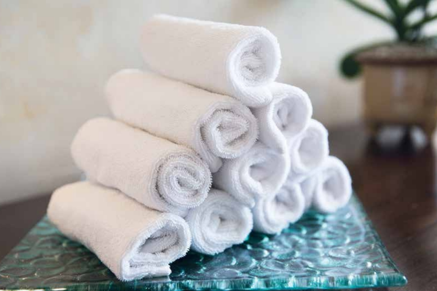 Stack of folded towels on a textured glass surface with a blurred background