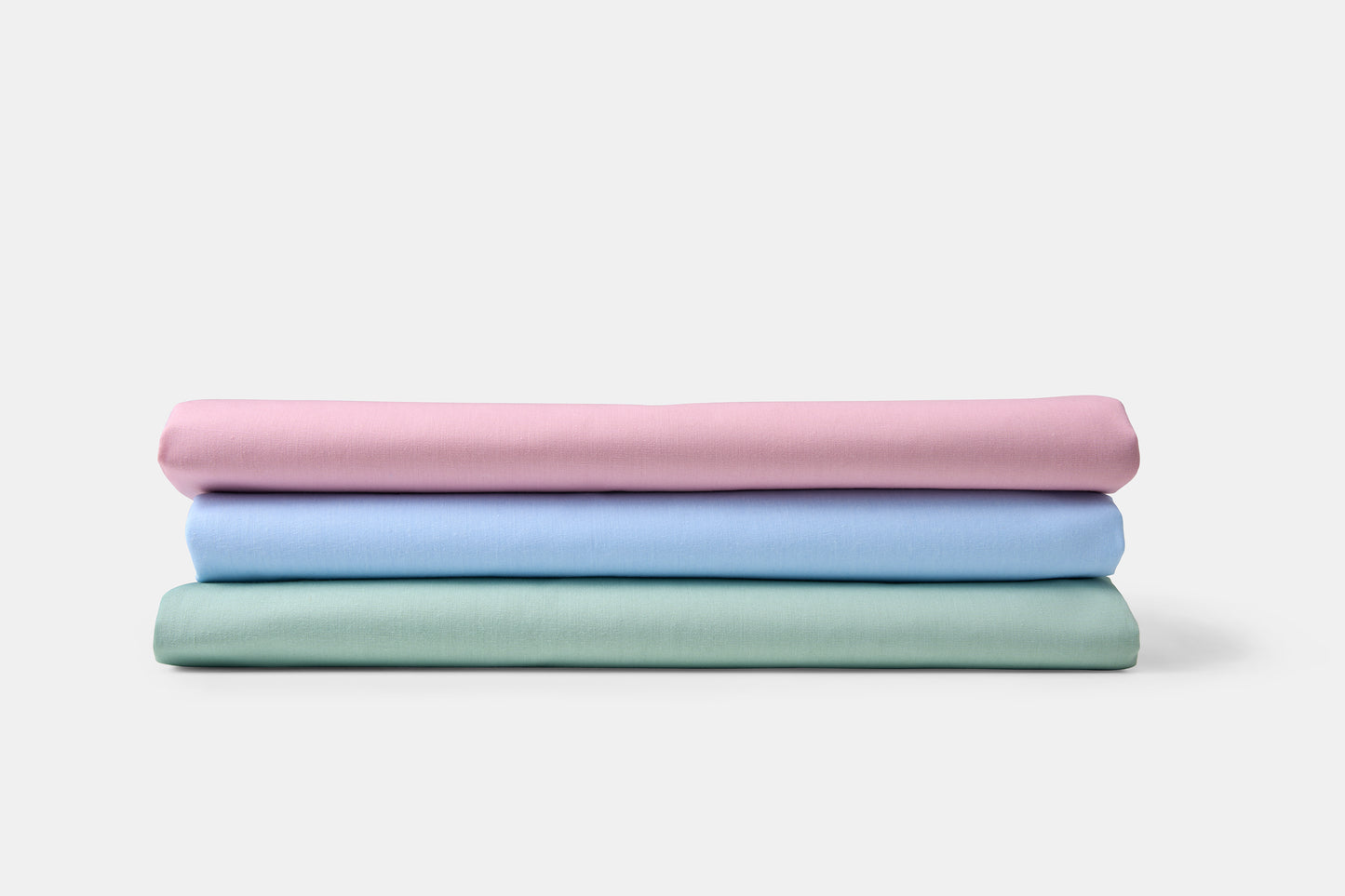 Stack of three folded fabrics in pink, blue, and green on a white background