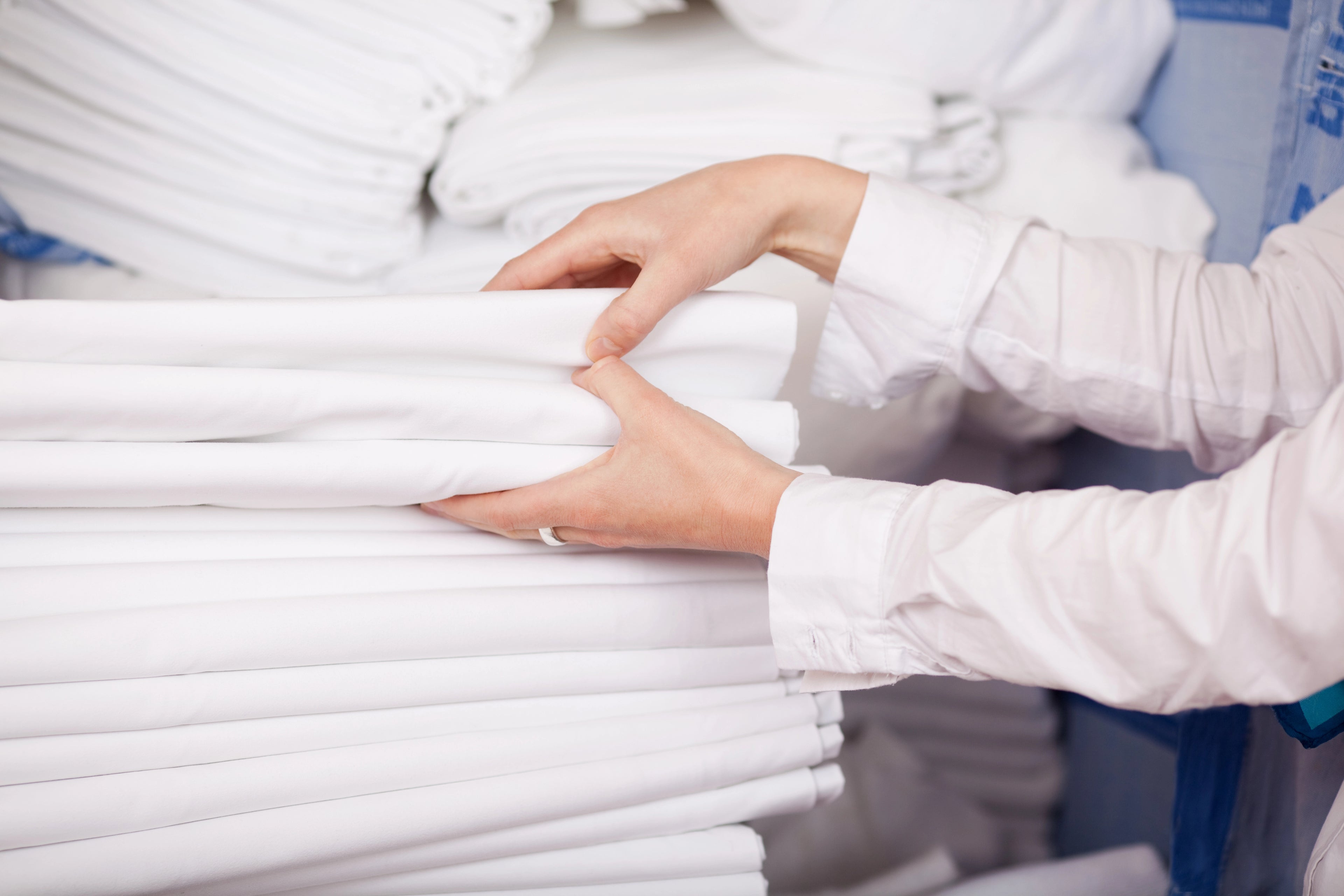 Person handling a stack of white linen