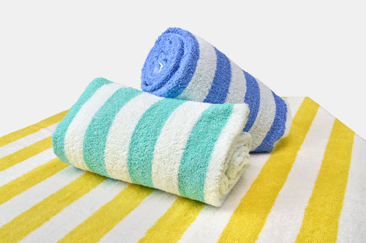 Two rolled-up beach towels with blue, green, and white stripes on a yellow and white striped background.