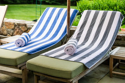 Two lounge chairs with striped towels on a patio