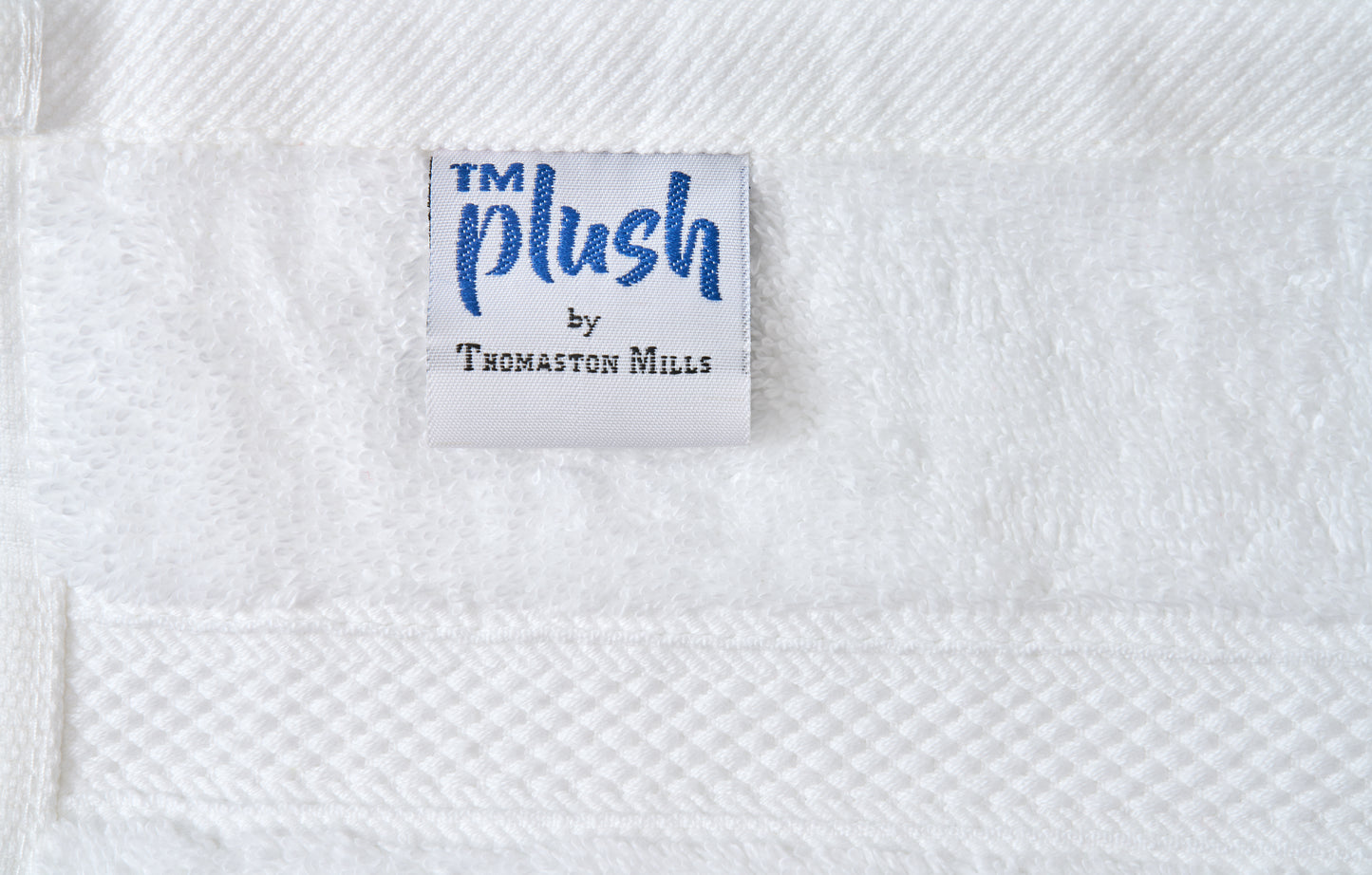 Label with 'TM Plush by Thomaston Mills' on a textured white fabric background