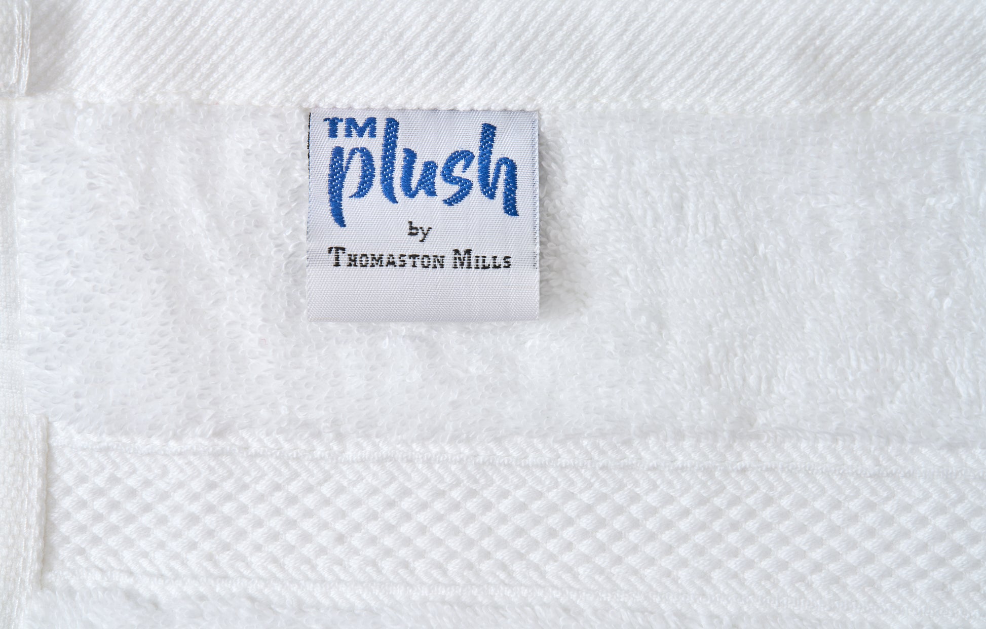 Label with 'TM Plush by Thomaston Mills' on a textured white fabric background