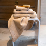 Thomaston Mills beige Royal Suite Dobby Towels draped and Folded over a stool.