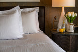 The edge of a bed made with Thomaston Mills duvet cover and pillow shams
