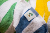 Blue island stripe pool towel displaying Island Stripe by Thomaston Mills label on top of a green and yellow island stripe pool towels