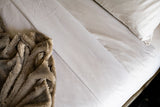 Corner of a bed made with Thomaston Mills Decorative Top Sheet and a brown throw.